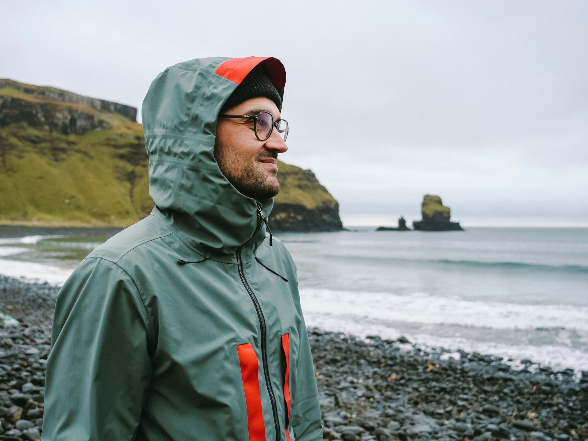 A man standing on a rocky beach next to the ocean
